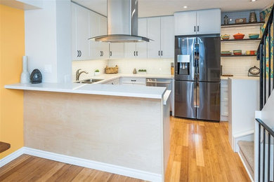 Kitchen - small contemporary u-shaped bamboo floor kitchen idea in Toronto with a double-bowl sink, shaker cabinets, white cabinets, quartz countertops, white backsplash, ceramic backsplash, stainless steel appliances and a peninsula