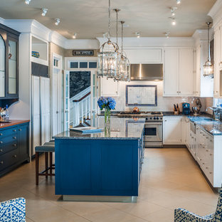 Expansive beach style u-shaped open plan kitchen in New York with a drop-in sink, flat-panel cabinets, white cabinets, granite benchtops, beige splashback, stone slab splashback, stainless steel appliances, terra-cotta floors and a peninsula.