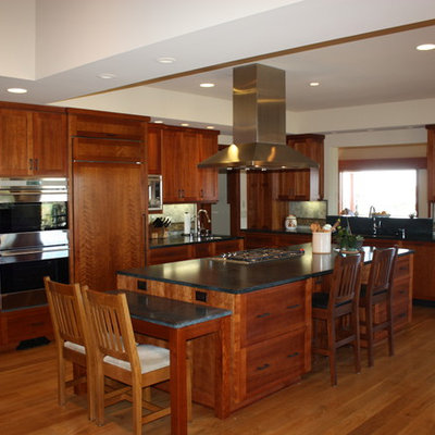 Example of a large arts and crafts l-shaped medium tone wood floor and brown floor eat-in kitchen design in San Diego with an undermount sink, shaker cabinets, dark wood cabinets, granite countertops, multicolored backsplash, porcelain backsplash, paneled appliances, an island and black countertops