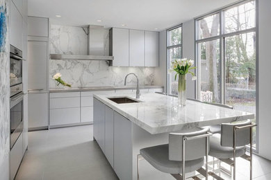Example of a small trendy galley porcelain tile kitchen pantry design in Boston with a drop-in sink, flat-panel cabinets, light wood cabinets, marble countertops, multicolored backsplash, stone slab backsplash, stainless steel appliances and an island