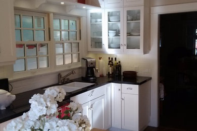 Klassische Küche mit Doppelwaschbecken, Glasfronten, weißen Schränken, Küchenrückwand in Weiß, Rückwand aus Metrofliesen, braunem Holzboden und Kücheninsel in Los Angeles
