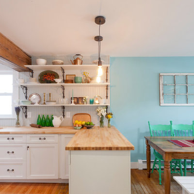 Inspiration for an eclectic l-shaped open concept kitchen remodel in New York with a farmhouse sink, shaker cabinets, white cabinets, wood countertops, gray backsplash and stainless steel appliances