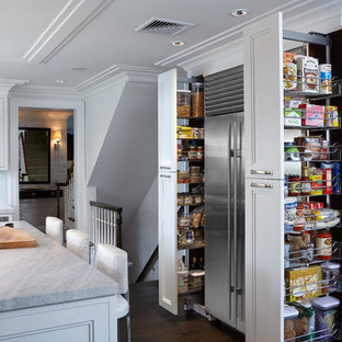 Large transitional l-shaped kitchen pantry in New York with an undermount sink, glass-front cabinets, white cabinets, marble benchtops, white splashback, glass tile splashback, stainless steel appliances, dark hardwood floors and with island.