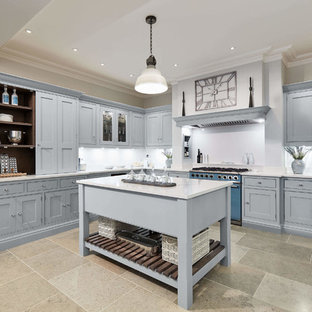 Large classic l-shaped kitchen in London with shaker cabinets, blue cabinets, quartz worktops, white splashback, coloured appliances, limestone flooring, an island, multi-coloured floors and white worktops.