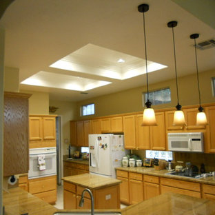 Design ideas for a mid-sized traditional u-shaped eat-in kitchen in Sacramento with a double-bowl sink, shaker cabinets, brown cabinets, granite benchtops, blue splashback, stone slab splashback, white appliances, porcelain floors, a peninsula and beige floor.