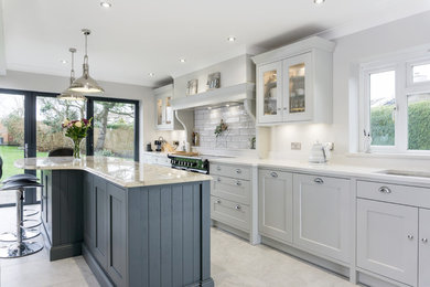 Photo of a large classic grey and white single-wall kitchen/diner in Other with a built-in sink, shaker cabinets, grey cabinets, engineered stone countertops, white splashback, ceramic splashback, black appliances, ceramic flooring, an island, grey floors and white worktops.