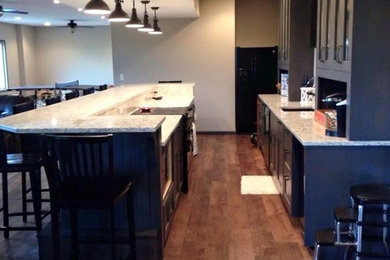Example of a mid-sized transitional u-shaped dark wood floor and brown floor eat-in kitchen design in San Diego with a double-bowl sink, recessed-panel cabinets, dark wood cabinets, granite countertops, gray backsplash, ceramic backsplash, stainless steel appliances and an island