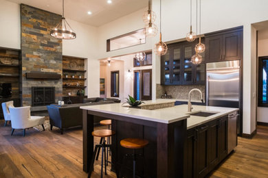 Open concept kitchen - large rustic l-shaped medium tone wood floor open concept kitchen idea in Portland with an integrated sink, recessed-panel cabinets, black cabinets, quartzite countertops, multicolored backsplash, mosaic tile backsplash, stainless steel appliances and an island