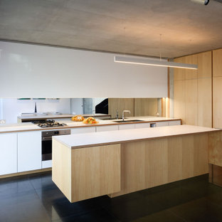 Photo of a large modern galley eat-in kitchen in Sydney with an undermount sink, light wood cabinets, laminate benchtops, mirror splashback, stainless steel appliances, with island, black floor and white benchtop.