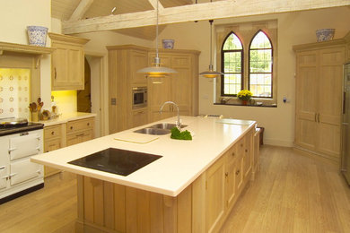 Photo of a contemporary kitchen in Dorset with composite countertops, light hardwood flooring and an island.