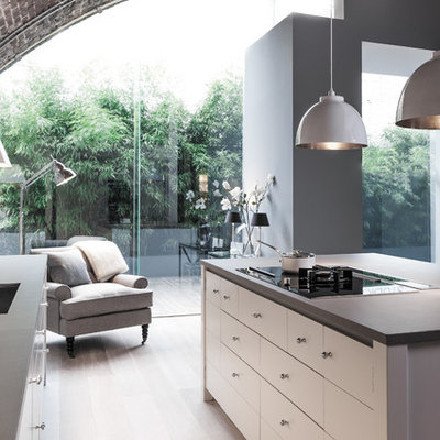Trendy galley medium tone wood floor and brown floor open concept kitchen photo in London with an undermount sink, flat-panel cabinets, white cabinets, red backsplash, brick backsplash and an island