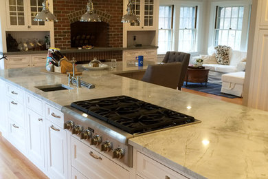 Example of a mid-sized classic u-shaped light wood floor open concept kitchen design in Boston with an undermount sink, raised-panel cabinets, white cabinets, quartzite countertops, white backsplash, subway tile backsplash, stainless steel appliances and an island