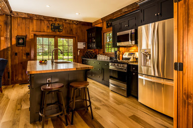Example of a farmhouse medium tone wood floor kitchen design in Burlington with an undermount sink, shaker cabinets, distressed cabinets, granite countertops, brick backsplash, stainless steel appliances and an island