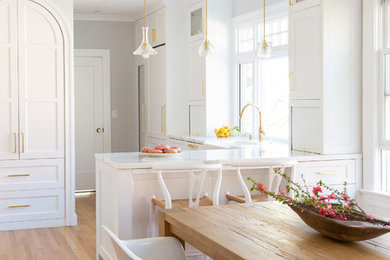 Inspiration for a mid-sized scandinavian l-shaped medium tone wood floor eat-in kitchen remodel in San Francisco with a farmhouse sink, recessed-panel cabinets, white cabinets, marble countertops and marble backsplash
