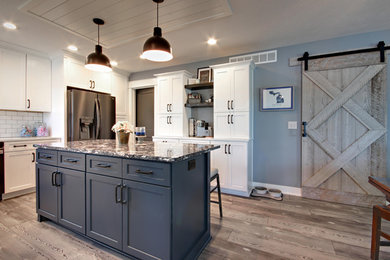 Eat-in kitchen - mid-sized country u-shaped vinyl floor and gray floor eat-in kitchen idea in Grand Rapids with an undermount sink, recessed-panel cabinets, white cabinets, quartz countertops, white backsplash, subway tile backsplash, black appliances, an island and white countertops