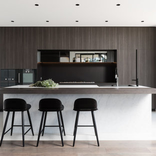 Photo of a contemporary kitchen in Sydney with a drop-in sink, flat-panel cabinets, dark wood cabinets, black appliances, with island and white floor.