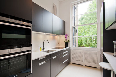Пример оригинального дизайна: параллельная кухня в современном стиле с врезной мойкой, плоскими фасадами, черной техникой и черно-белыми фасадами без острова