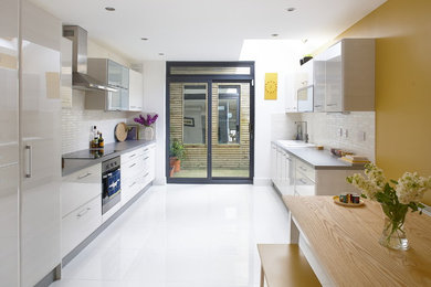 Ejemplo de cocina contemporánea con armarios con paneles lisos, puertas de armario blancas, salpicadero amarillo, salpicadero de azulejos tipo metro, electrodomésticos de acero inoxidable y suelo blanco