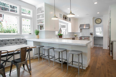 Inspiration for a mid-sized transitional u-shaped medium tone wood floor and brown floor eat-in kitchen remodel in Los Angeles with an undermount sink, recessed-panel cabinets, white cabinets, granite countertops, white backsplash, subway tile backsplash, stainless steel appliances, a peninsula and gray countertops