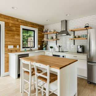 Design ideas for a mid-sized country l-shaped kitchen in DC Metro with shaker cabinets, white cabinets, wood benchtops, white splashback, subway tile splashback, stainless steel appliances, with island, brown benchtop, an undermount sink and beige floor.