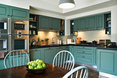 This is an example of a medium sized contemporary u-shaped kitchen/diner in London with a submerged sink, green cabinets, marble worktops, green splashback, ceramic splashback, stainless steel appliances and dark hardwood flooring.