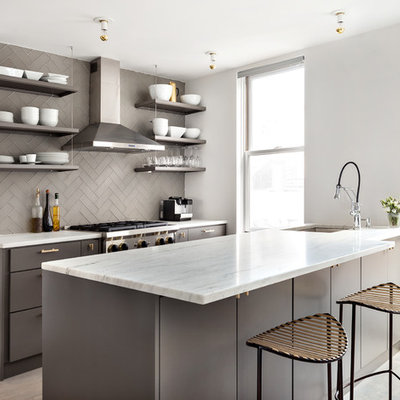 Example of a small trendy galley light wood floor open concept kitchen design in New York with an undermount sink, flat-panel cabinets, gray cabinets, gray backsplash, subway tile backsplash, stainless steel appliances and a peninsula