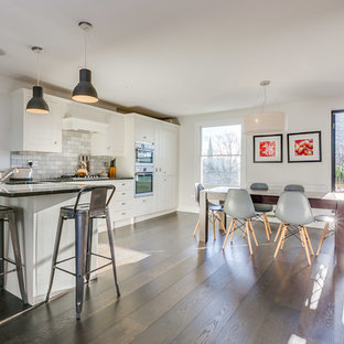 Inspiration for a medium sized contemporary l-shaped kitchen/diner in London with white cabinets, marble worktops, grey splashback, marble splashback, stainless steel appliances, dark hardwood flooring, a breakfast bar, brown floors, black worktops, a submerged sink and shaker cabinets.