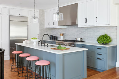 Inspiration for a transitional medium tone wood floor and orange floor kitchen remodel in Manchester with an undermount sink, blue cabinets, gray backsplash, subway tile backsplash, stainless steel appliances, an island and white countertops
