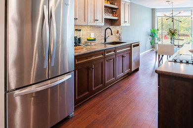 Open concept kitchen - mid-sized transitional galley vinyl floor and brown floor open concept kitchen idea in New York with an undermount sink, shaker cabinets, dark wood cabinets, laminate countertops, multicolored backsplash, brick backsplash, stainless steel appliances, an island and gray countertops