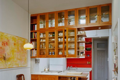 Ejemplo de cocina de tamaño medio abierta con armarios tipo vitrina, puertas de armario de madera clara, encimera de terrazo, salpicadero rojo, suelo de madera en tonos medios y península