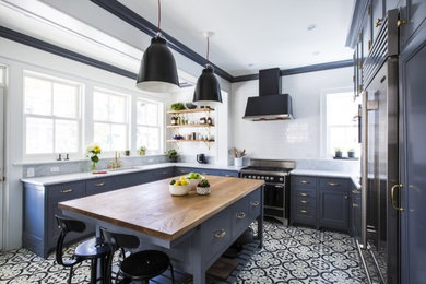 Example of a mid-sized transitional u-shaped porcelain tile and multicolored floor eat-in kitchen design in Los Angeles with an undermount sink, shaker cabinets, blue cabinets, wood countertops, stainless steel appliances and an island