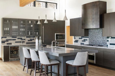 Eat-in kitchen - large contemporary l-shaped light wood floor, brown floor and exposed beam eat-in kitchen idea in Denver with an undermount sink, flat-panel cabinets, dark wood cabinets, blue backsplash, ceramic backsplash, stainless steel appliances, an island and white countertops