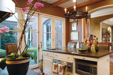 Foto di un piccolo cucina con isola centrale tradizionale con lavello sottopiano, ante bianche, elettrodomestici in acciaio inossidabile, pavimento in legno massello medio e pavimento marrone
