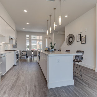 Open concept kitchen pictures - Example of a single-wall light wood floor and gray floor open concept kitchen design in San Francisco with flat-panel cabinets, white cabinets, white backsplash, stainless steel appliances and an island