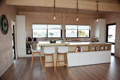 Foto di una cucina minimalista di medie dimensioni con lavello a vasca singola, ante lisce, elettrodomestici in acciaio inossidabile, pavimento in laminato, pavimento marrone e top beige
