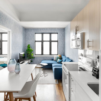 Inspiration for a small contemporary single-wall light wood floor and beige floor eat-in kitchen remodel in New York with an undermount sink, flat-panel cabinets, light wood cabinets, solid surface countertops, white backsplash, ceramic backsplash, white appliances, no island and white countertops