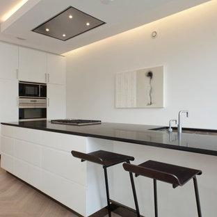 This is an example of a contemporary kitchen in Amsterdam with flat-panel cabinets, white cabinets and black benchtop.