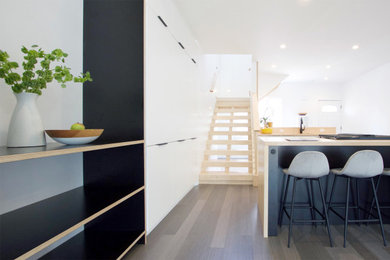 Idéer för ett litet modernt kök, med en undermonterad diskho, släta luckor, vita skåp, träbänkskiva, rostfria vitvaror, bambugolv, en köksö och grått golv