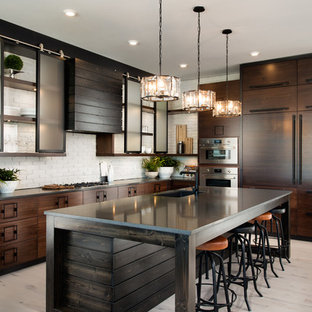 Immagine di una grande cucina industriale con lavello sottopiano, ante lisce, ante in legno bruno, paraspruzzi bianco, paraspruzzi in mattoni, elettrodomestici da incasso, parquet chiaro, isola, pavimento beige e top in saponaria