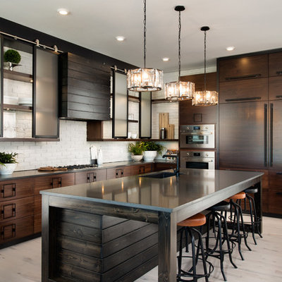 Eat-in kitchen - large industrial l-shaped light wood floor and beige floor eat-in kitchen idea in Other with an undermount sink, flat-panel cabinets, dark wood cabinets, white backsplash, brick backsplash, paneled appliances, an island and soapstone countertops