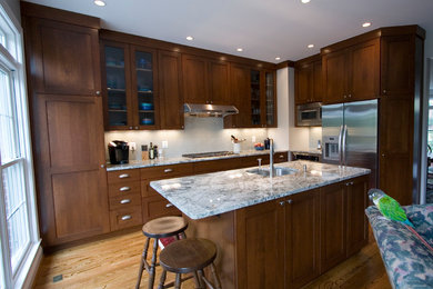 Mid-sized transitional l-shaped medium tone wood floor and brown floor kitchen photo in DC Metro with an undermount sink, shaker cabinets, dark wood cabinets, granite countertops, white backsplash, glass tile backsplash, stainless steel appliances and an island