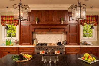 Photo of a large classic u-shaped enclosed kitchen in Chicago with a submerged sink, raised-panel cabinets, dark wood cabinets, engineered stone countertops, beige splashback, ceramic splashback, stainless steel appliances, ceramic flooring and an island.