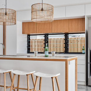 Inspiration for a beach style kitchen in Gold Coast - Tweed with a drop-in sink, flat-panel cabinets, medium wood cabinets, window splashback, stainless steel appliances, grey floor and white benchtop.