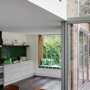 Eclectic kitchen in London with flat-panel cabinets, white cabinets, green splashback and subway tile splashback.