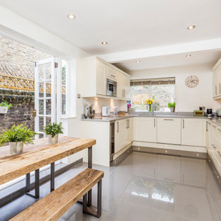 Photo of a traditional u-shaped kitchen/diner in London with a submerged sink, shaker cabinets, white cabinets, stainless steel appliances, no island, grey floors and grey worktops.