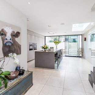 Photo of a contemporary galley kitchen in Sussex with a submerged sink, flat-panel cabinets, grey cabinets, black appliances, an island, grey floors and grey worktops.