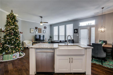 Mid-sized transitional l-shaped medium tone wood floor and brown floor open concept kitchen photo in Dallas with a farmhouse sink, shaker cabinets, white cabinets, granite countertops, subway tile backsplash, stainless steel appliances, an island and white countertops