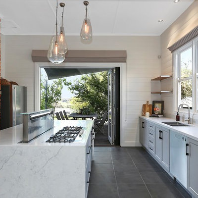 Example of a transitional galley gray floor kitchen design in Geelong with a double-bowl sink, recessed-panel cabinets, gray cabinets, white backsplash, stainless steel appliances, an island and white countertops