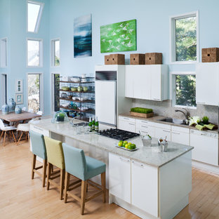 Inspiration for a large beach style galley eat-in kitchen in New York with flat-panel cabinets, white cabinets, light hardwood floors, an undermount sink, quartzite benchtops, white splashback, stone slab splashback, white appliances, with island, beige floor and white benchtop.
