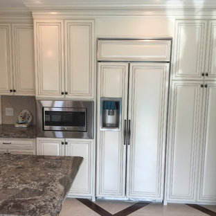 Photo of a mid-sized victorian u-shaped separate kitchen in Los Angeles with a farmhouse sink, raised-panel cabinets, beige cabinets, granite benchtops, beige splashback, mosaic tile splashback, panelled appliances, marble floors, with island and beige floor.